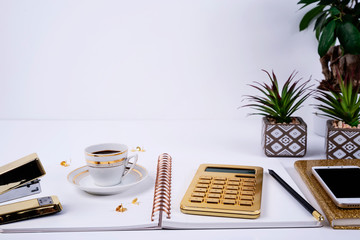 Modern office desk with notebook, plant, calculator, pencil and white copy space on the wall. ...