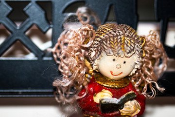 Christmas angel made of porcelain with synthetic hair reads in a book
