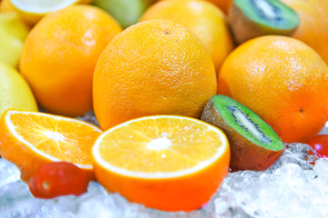 Various refreshing citrus fruits inside cold ice in close-up.
