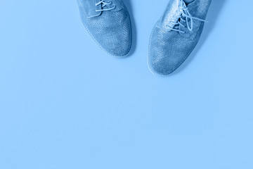 Pair of gradient blue suede shoes on trending monochrome color background. Minimalistic flat lay with copy space. Hipster blog advert or shoe fashion or repair service concept banner