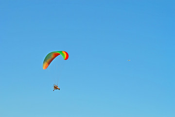Fototapeta na wymiar paramotor with paraglider pilot on blue sky, motor hang glide tricycle with colorful sail, extreme sport diversirty