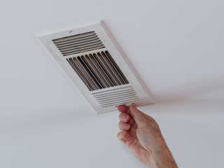 Handyman adjusting HVAC ceiling air vent. Air flow adjustment for overhead home heat and air...