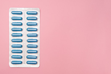 Antibiotics and antimicribial pills for treatment sexually transmitted diseases STD, blue capsules in blister on pink background, copy space