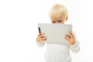 Little blonde caucasian boy look at the tablet isolated on white background