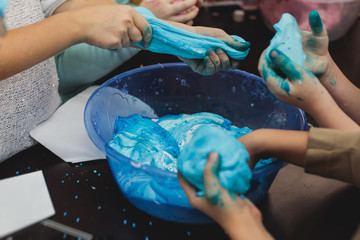 Group of kids making a multicoloured slime, pink, blue and white slime toy on kids birthday party,...