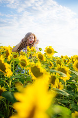 Fototapeta na wymiar Happy girl with blond long hair on a field of sunflowers