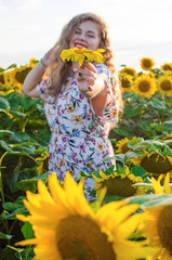 Happy girl with blond long hair on a field of sunflowers