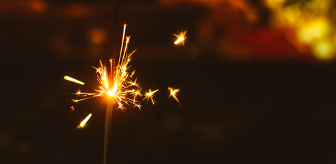 Sparklers for Christmas and New Year close-up on a holiday background in warm colors, wide photo