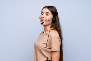 Young woman over isolated blue background working with headset