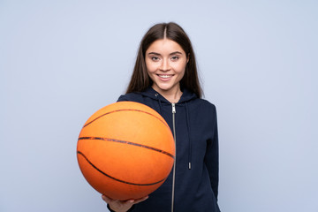 Young woman over isolated blue background with ball of basketball