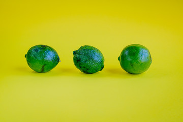 Trendy ugly lime on the yellow background - concept of zero waste life. Copy space.
