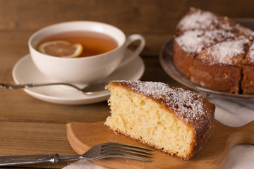 piece of homemade lemon pie and a cup of tea on a wooden background