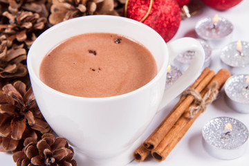 Cup of hot chocolate ,  some cinnamon sticks, cones, christmas balls and candles