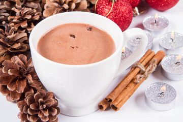 Cup of hot chocolate ,  some cinnamon sticks, cones, christmas balls and candles