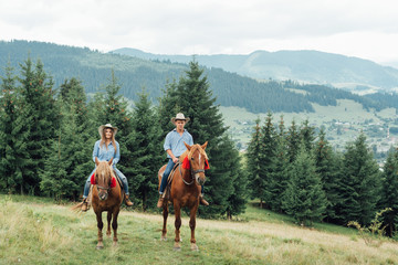 Couple riding horses in countryside tour - Happy people having fun on summer day outdoor -...