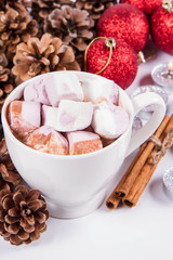 Cup of hot chocolate with marshmallows ,  some cinnamon sticks, cones, christmas balls and candles