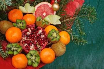 a large bouquet of colored fresh fruits and coniferous branches on a green background