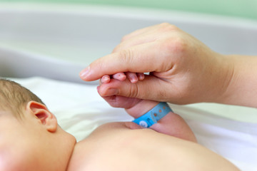 The baby clings to his mother's finger