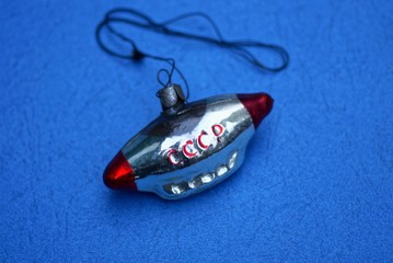old soviet christmas toy in the form of a spaceship lies on a blue table