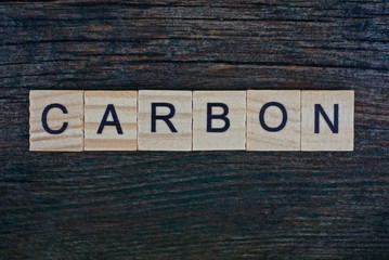 word carbon made from wooden gray letters lies on a gray background