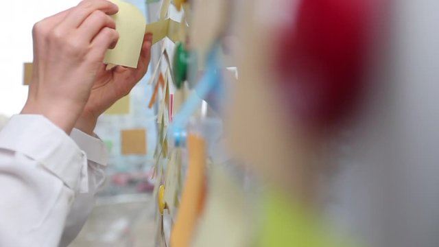 Business woman writes notes using post stickers on paper. Brainstorming, teamwork.