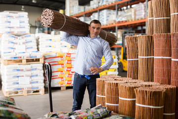 Male buyer chooses decorative wicker fence in hardware store