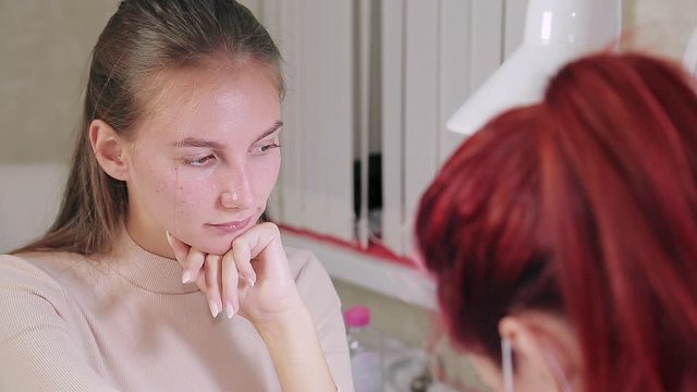 A client of a beauty salon during the procedure for preparing nails for gel polish. Transfer of focus from hand to face