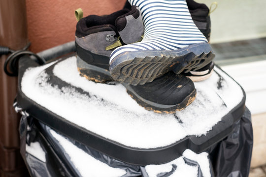 abandoned boots on a top of garbade bin