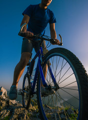Fototapeta na wymiar Close up silhouette of an athlete (mountain biker) riding his bike on rocky mountains.