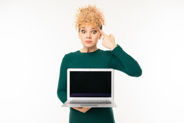 curly blonde girl holding a laptop with mockup with the screen forward on a white wall