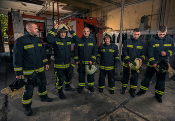 Portrait of firefighters standing by a fire engine.