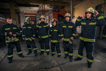 Portrait of firefighters standing by a fire engine.