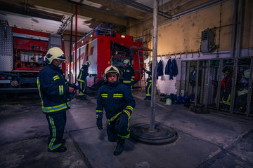 Naklejka premium Firefighters preparing their uniform and the firetruck in the background inside the fire station