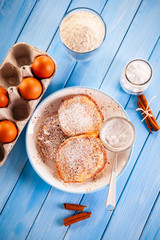 Sweet pancakes and ingredients on timber background