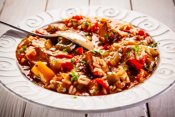 Roast pork meat with rice and vegtables on wooden background