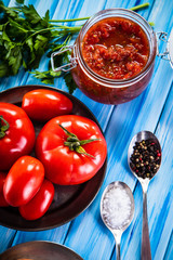 Raw tomatoes and tomato sauce in jar on wooden background