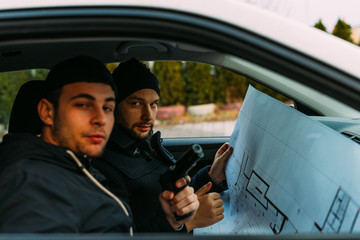 Two Thieves parked in an ally waiting while talking on the phone, observing their target and...