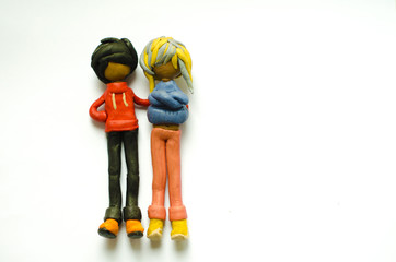 Plasticine figurines guy and girl on a white background. The guy put his hand on the shoulder of...