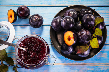 Plums and preserves on wooden background