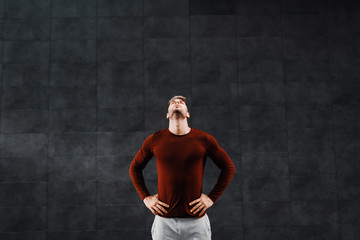 Obraz premium Attractive fit caucasian breaded sportsman in tracksuit holding hands on hips and doing warm up exercises for neck before running.