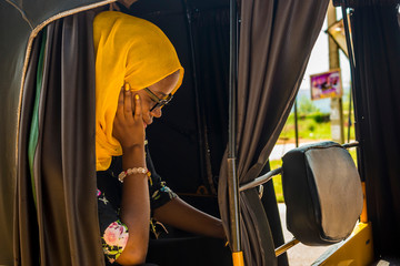 young african woman sitting alone in a rickshaw looking sad and tired