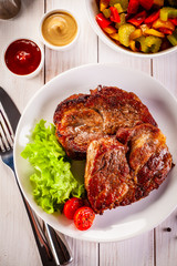 Grilled steak and vegetables on wooden background