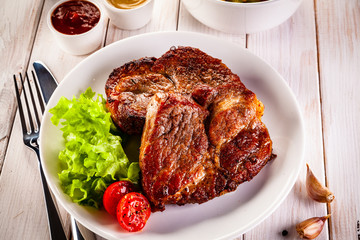 Grilled steak and vegetables on wooden background