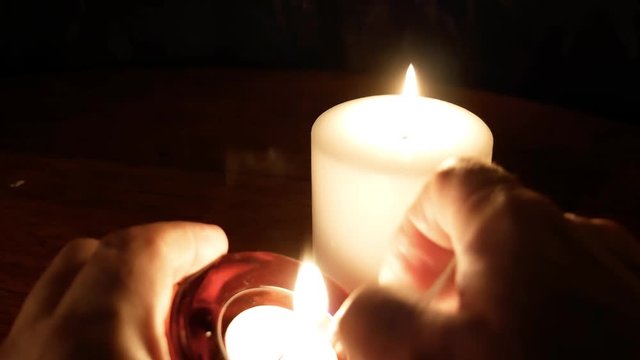 Person Lights Votive Candle and Places Near Larger Burning Candle