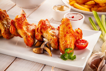 Barbecued chicken wings with french fries and vegetable salad on timber