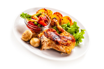 Barbecued chicken leg with chips and vegetables on white background