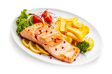 Roast salmon, french fries and vegetables on white background