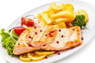 Roast salmon, french fries and vegetables on white background