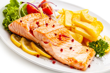 Roast salmon, french fries and vegetables on white background