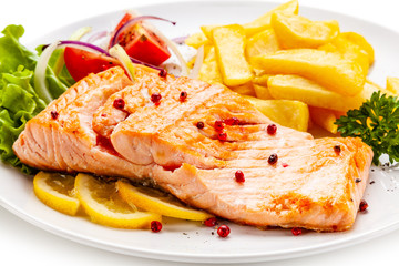 Roast salmon, french fries and vegetables on white background